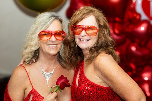 Two women wearing red sunglasses